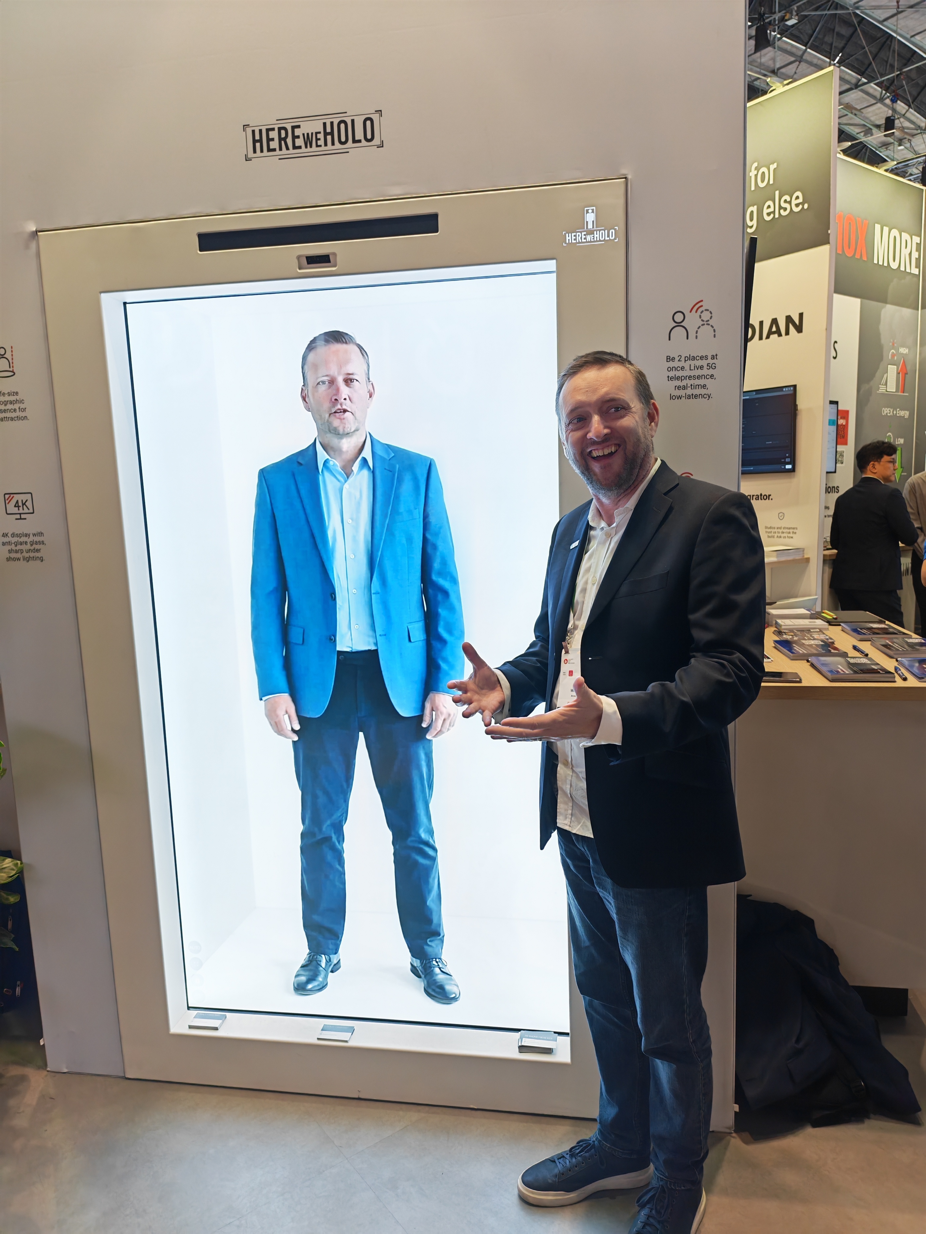 2. Arcadian's Joe Waltzer with NETINT's HEREweHOLO life-size holographic telepresence display on the stand.